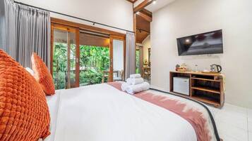 Ein Hotelzimmer mit einem großen Bett, einem Fernseher und einer Schiebetür zu einem Garten.