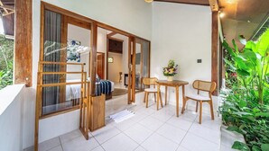 A room with a sliding door leading to a balcony, a small table with chairs, and a potted plant. - -20% OFF NEW Cozy 1BR in Ubud w Pool, Garden&Patio (Ubud)