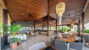 A spacious indoor area with a high ceiling, wooden beams, and a mix of seating arrangements including tables and chairs.