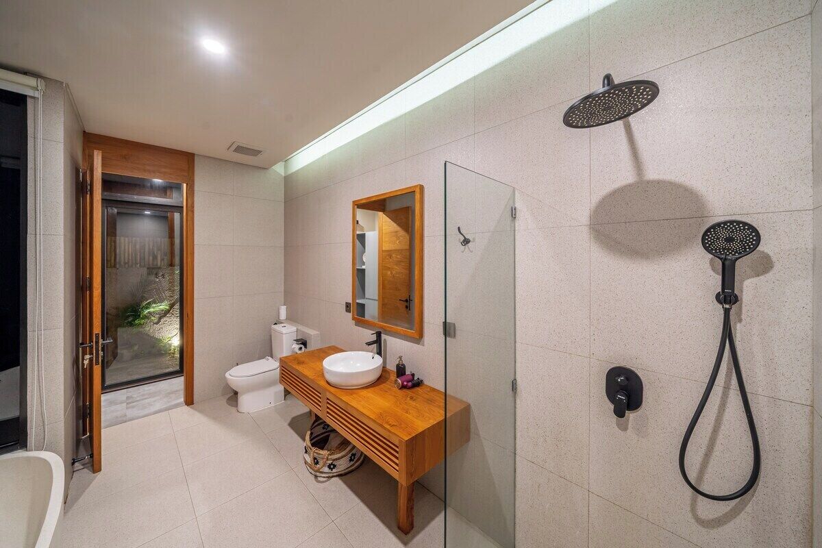 Ein modernes Badezimmer mit Duschkabine aus Glas, einem Holzbadezimmermöbel und einer weißen Toilette.