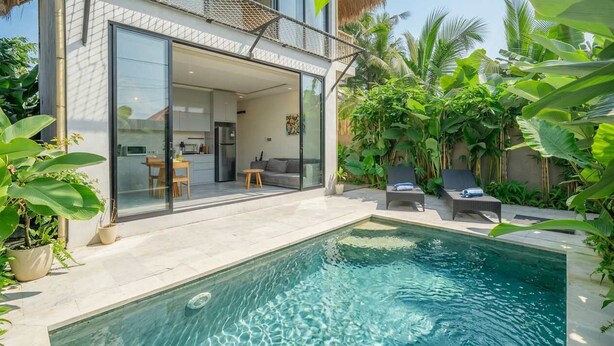A modern house with a glass-enclosed patio, a swimming pool, and lush tropical plants. - New Tropical Villa+Large Pool+Perfect for Couples (Gianyar Regency)