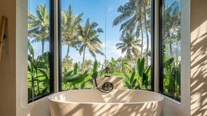A modern bathroom with a freestanding bathtub, large windows, and a view of palm trees. - New Tropical Villa+Large Pool+Perfect for Couples (Gianyar Regency)