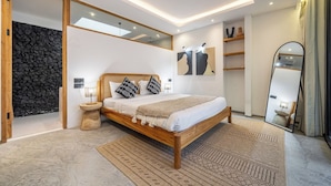 Ein modernes Schlafzimmer mit einem hölzernen Bett, einer Steinwand und einem großen Spiegel.