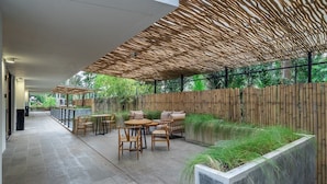 Ein Außenbereich mit Terrasse, Bambusfußboden, Holzmöbeln und einem Betonpflanzgefäß mit Gras.