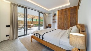A modern bedroom with a large bed, a nightstand, a lamp, and a sliding glass door leading to an outdoor area. - New private apartments in Ubud, best location (Gianyar Regency)