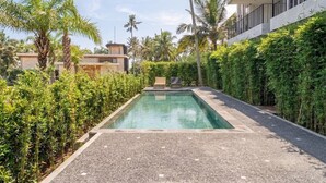 A swimming pool with a paved deck, surrounded by lush greenery and palm trees. - New private apartments in Ubud, best location (Gianyar Regency)
