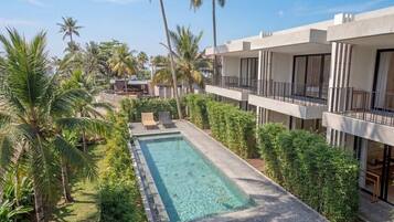 Un hôtel moderne doté d’une piscine, de palmiers et offrant une vue sur un ciel dégagé.