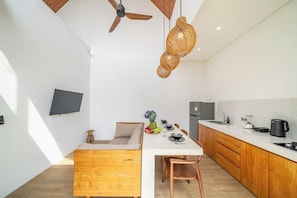 Cuina moderna amb armaris de fusta, una taula de dinar i un ventilador de sostre.