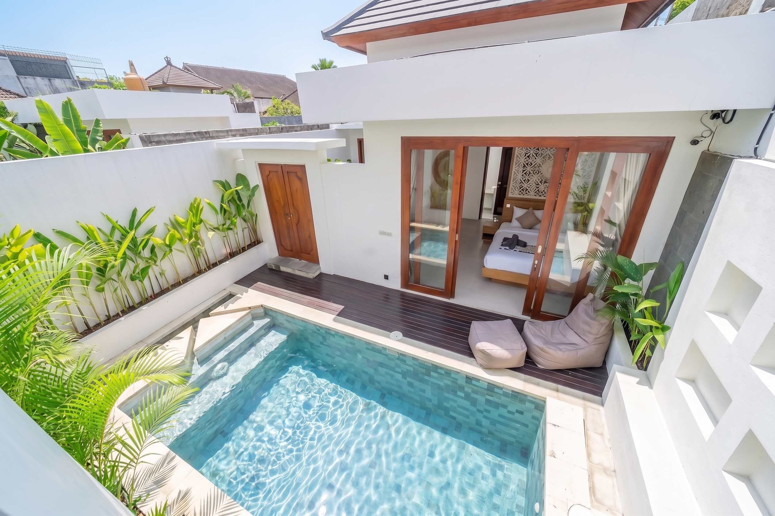 Ein moderner Poolbereich mit klarem Wasser, umgeben von üppiger Bepflanzung und einer Holzterrasse.