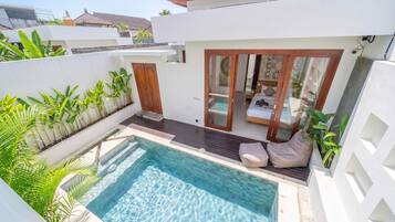 Ein moderner Poolbereich mit klarem Wasser, umgeben von üppiger Bepflanzung und einer Holzterrasse.