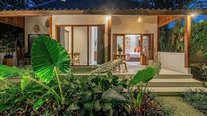 Una casa con un porche cubierto, un comedor y un dormitorio visibles a través de las puertas correderas.