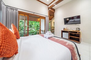 A hotel room with a large bed, a television, and a view of greenery outside. - Boutique 1BR in Central Ubud w Pool, Patio&Balcony (Kabupaten Gianyar)
