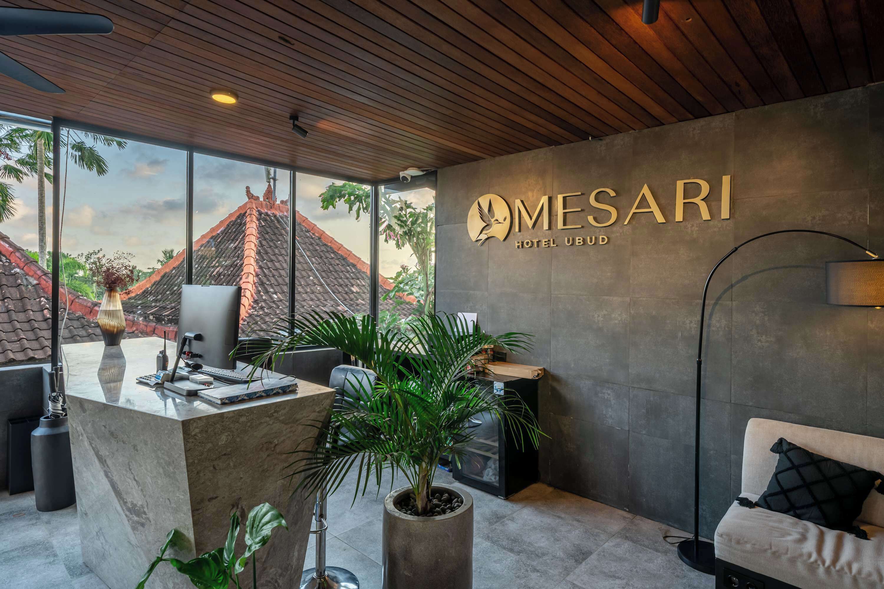 Un moderno vestíbulo de hotel con mostrador de recepción, zona de estar y grandes ventanales que ofrecen vistas al exterior.