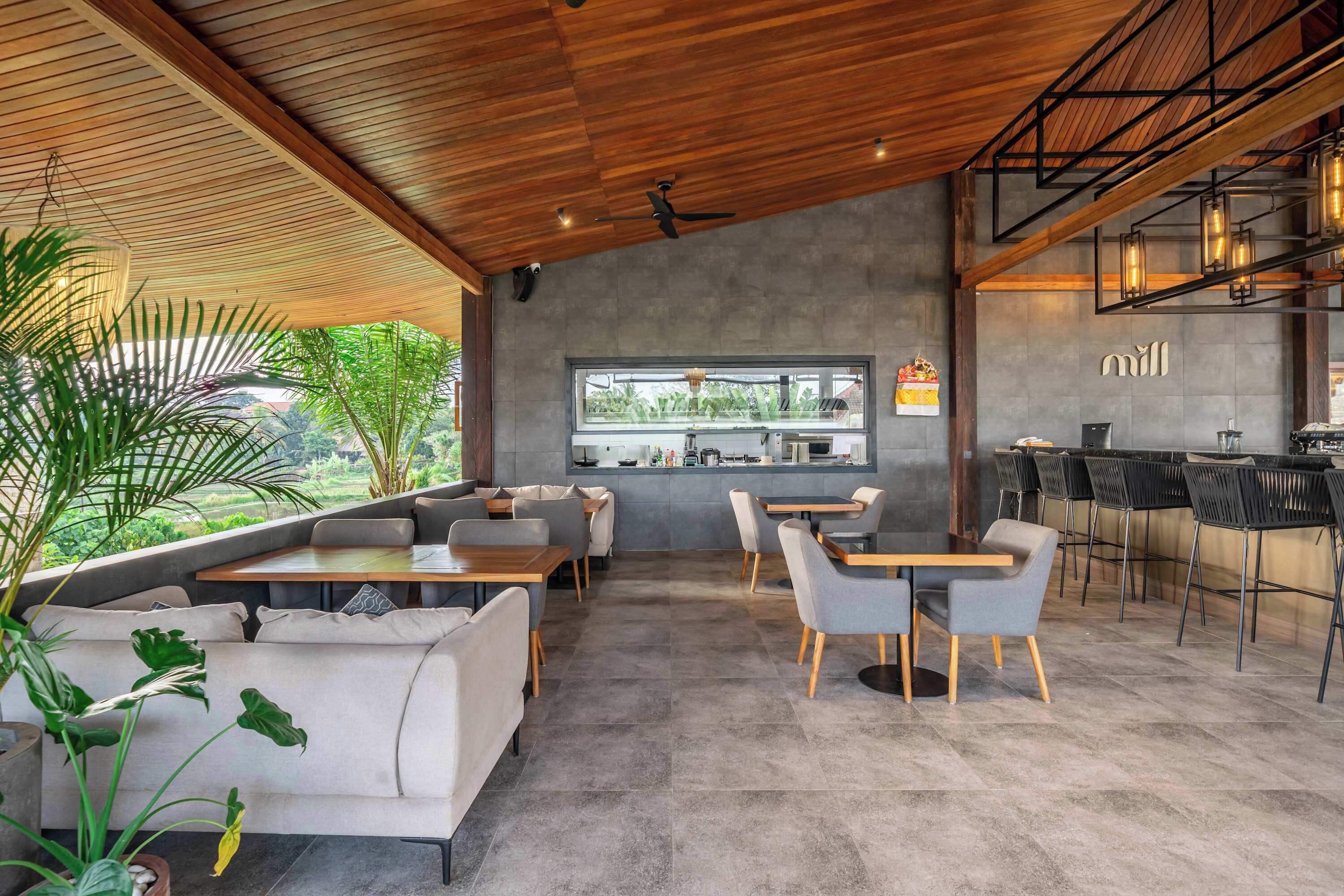 Un café moderne avec un plafond en bois, un espace salon avec des tables et des chaises, un bar avec des tabourets et une vue sur l’extérieur.