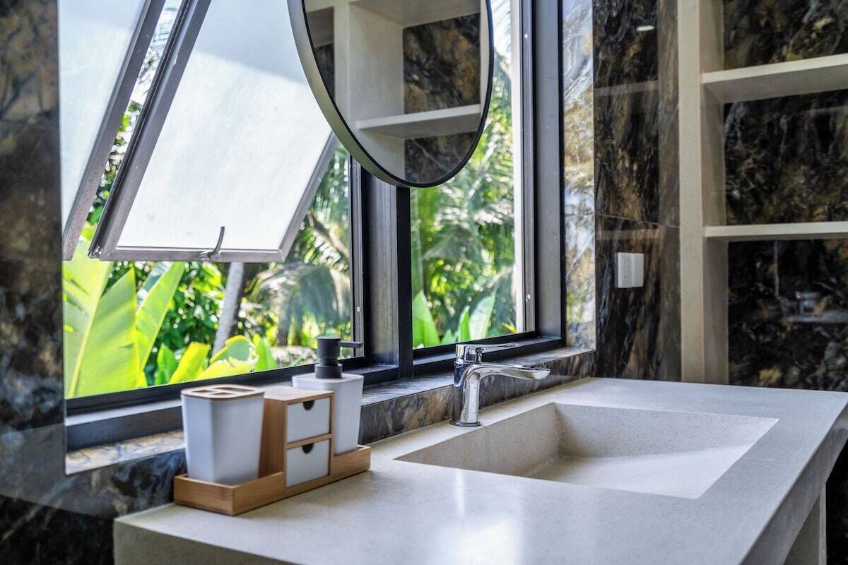 Ein Badezimmer mit großem Fenster, Waschbecken und Spiegel.