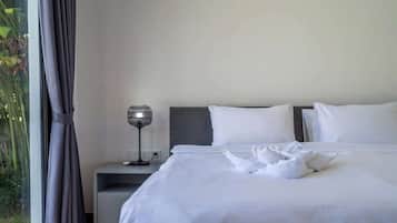 A hotel room with a bed, a bedside table with a lamp, and a window with curtains.