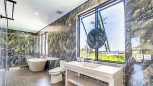 A modern bathroom with a freestanding bathtub, a large mirror, and a vanity with a sink. - Serene 3BR Villa w Huge Pool+Garden • Central Ubud (Sukawati)