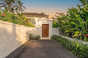 A villa entrance with a wooden door, a sign reading 'Royal Lotus,' and lush tropical vegetation. - Serene 3BR Villa w Huge Pool+Garden • Central Ubud (Sukawati)