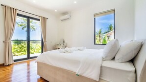 A bedroom with a large bed, a window with a view, and an air conditioning unit. - Serene 3BR Villa w Huge Pool+Garden • Central Ubud (Sukawati)