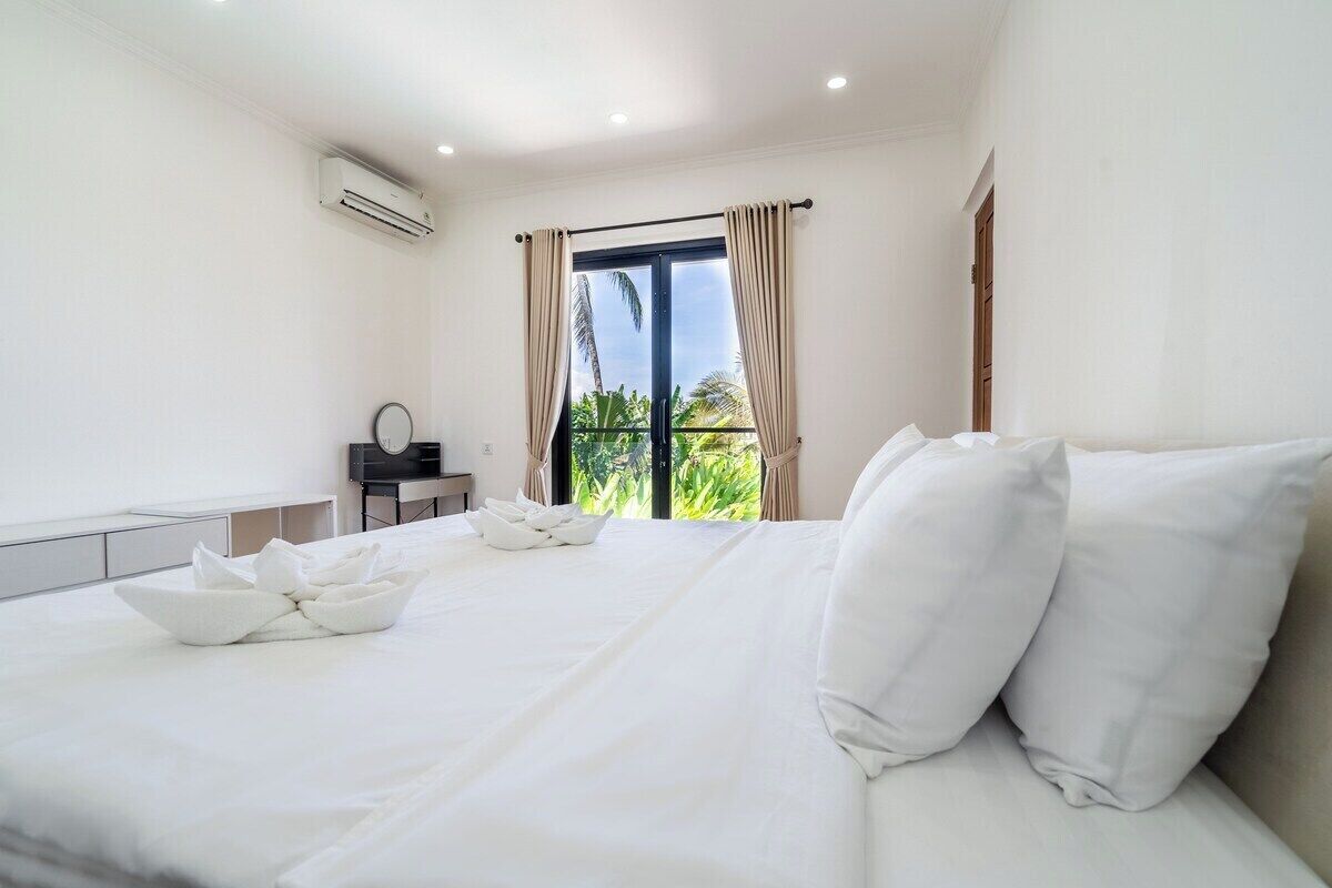 Ein Hotelzimmer mit einem großen Bett, einem Schreibtisch und einem fenster mit Vorhängen.