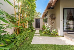 A pathway leading to a building with a thatched roof, surrounded by lush greenery and bamboo. - Peaceful 1BR Villa in Lush Ubud w Pool & Garden (Gianyar Regency)