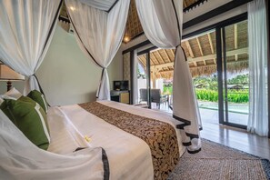 Une chambre d’hôtel avec un lit, des rideaux, une télévision et vue sur le jardin.