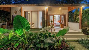 Una casa con un porche cubierto, un comedor y un dormitorio visibles a través de las puertas correderas.
