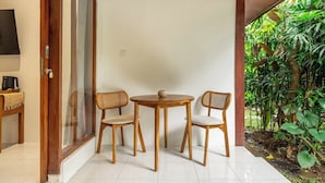 Una habitación con una mesa y sillas de madera, un televisor en la pared y vistas al exterior con vegetación.