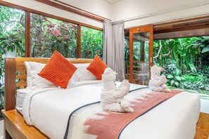 A bed with white bedding, orange pillows, and a wooden headboard. There are two towels folded on the bed. - Ubud's Best New 2BR w Spa, Pool & Lush Garden (Kabupaten Gianyar)