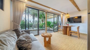 Ein modernes Wohnzimmer mit einer Couch, einem Esstisch mit Stühlen und einem an der Wand befestigten Fernseher.