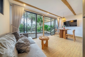 Una sala de estar moderna con un sofá, una mesa de comedor con sillas y un televisor montado en la pared.
