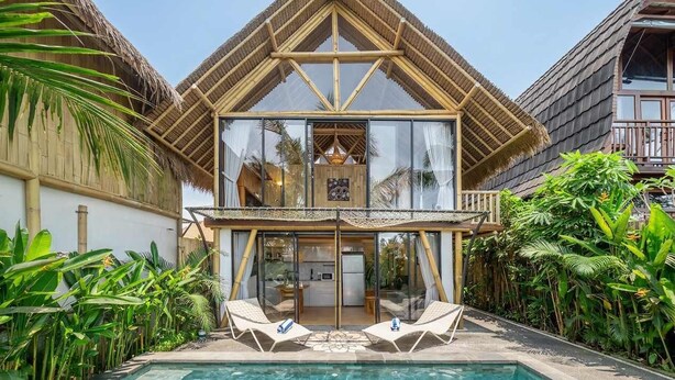 A two-story building with a thatched roof, a swimming pool, and two lounge chairs. - Tropical 1BR in Ubud w Pool - Perfect for Couples! (Tampaksiring)