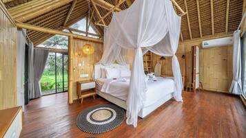 Ein Schlafzimmer mit Himmelsbett, Holzboden und Blick auf Grünfläche.