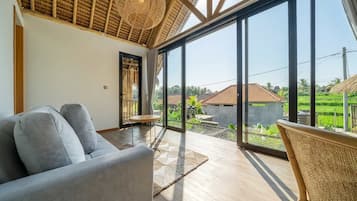 Un interior moderno con un ventanal grande, un sofá y una silla de mimbre.