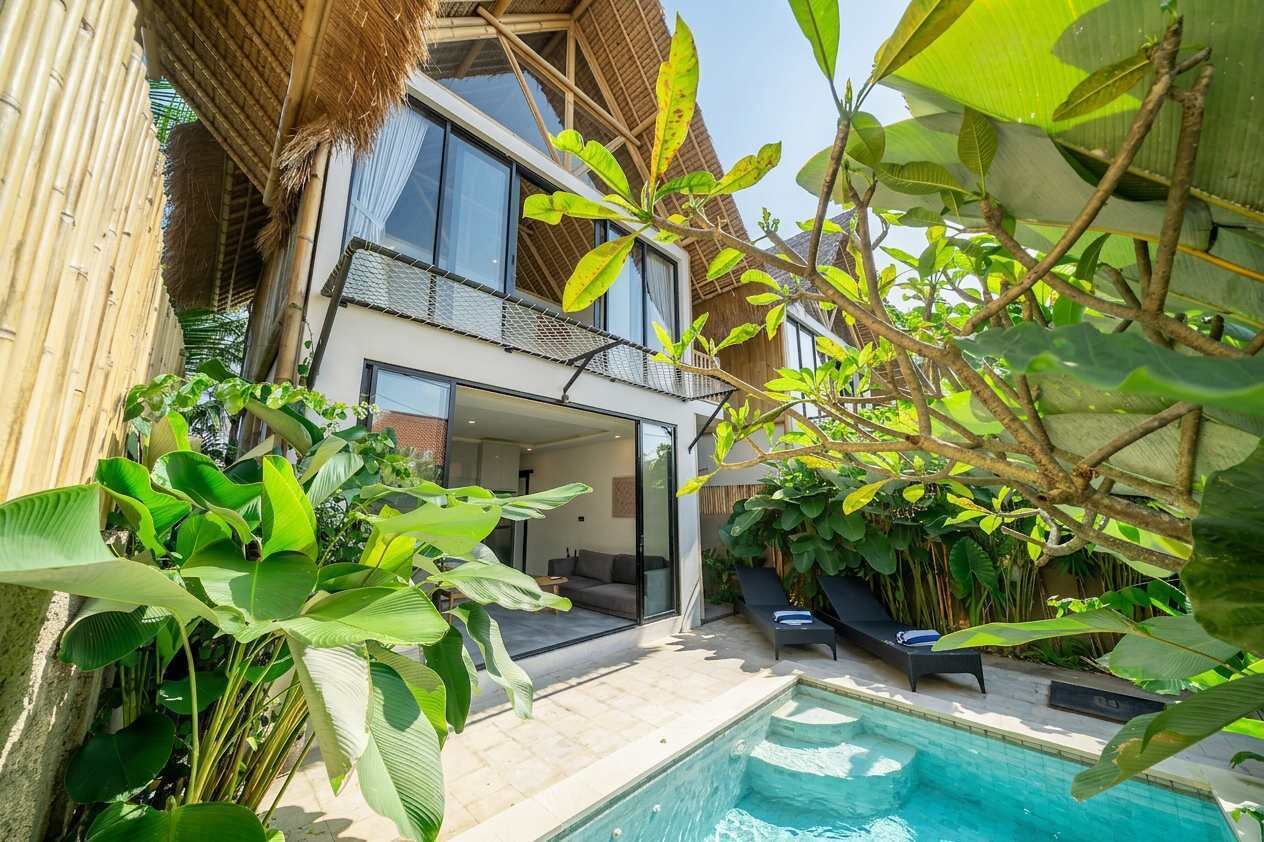 Ein modernes Haus mit Swimmingpool, umgeben von üppiger Vegetation und einem Reetdachdach.