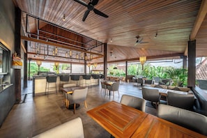 A spacious indoor area with a bar, seating, and a view of greenery.