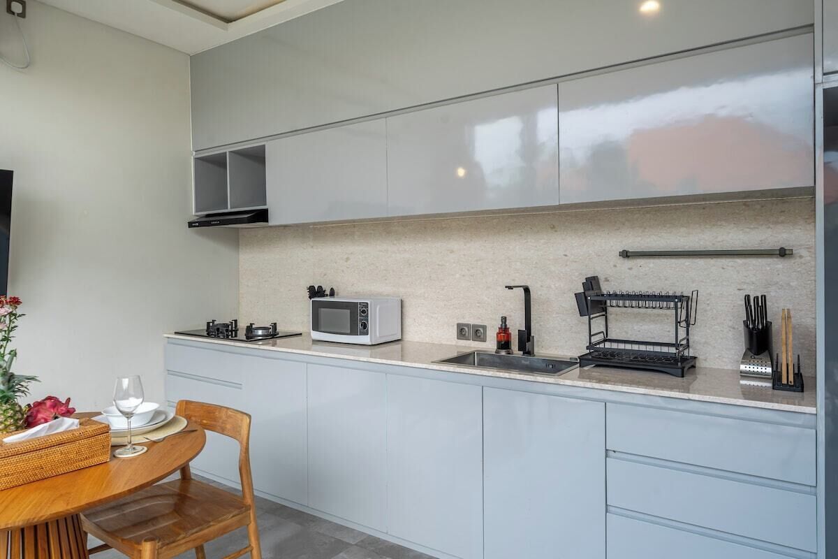 A modern kitchen with a microwave, sink, and utensil holder.