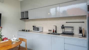 A modern kitchen with a microwave, sink, and utensil holder.