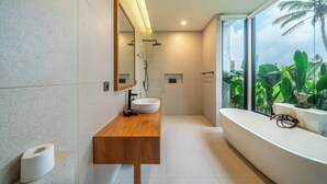 A modern bathroom with a wooden vanity, a large mirror, a freestanding bathtub, and a view of lush greenery outside. - Cozy 1BR in Ubud's Heart w Large Pool+Jungle View3 (Tampaksiring)
