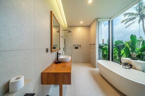 A modern bathroom with a wooden vanity, a large mirror, a freestanding bathtub, and a view of lush greenery outside. - Cozy 1BR in Ubud's Heart w Large Pool+Jungle View3 (Tampaksiring)