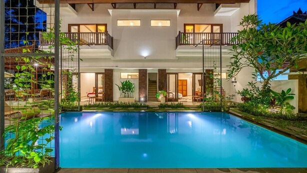 Un edificio de dos pisos con una piscina delantera.