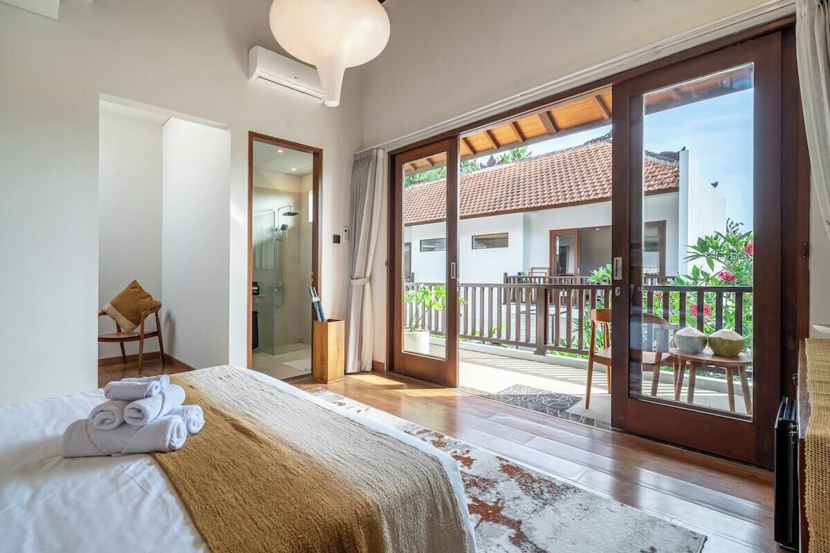Ett hotellrum med en säng, ett badrum och en balkong med utsikt över omgivningarna.
