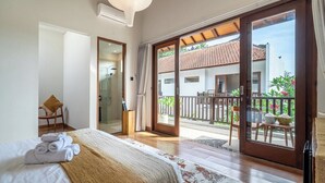 Habitación de hotel con cama, baño y balcón con vistas al exterior.