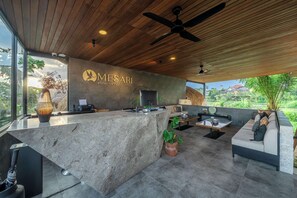 Zona de recepción con techo de madera, mostrador de recepción, sofá y vistas al exterior.