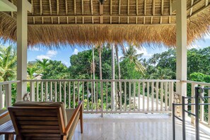 A covered outdoor seating area with a view of tropical vegetation. - Modern Ricefield View Suite in Mesari Hotel Ubud (Gianyar Regency)