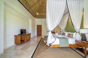 A room with a bed, a television on a wooden cabinet, a wooden door, and a large window with sheer curtains. - Cozy Room in Mesari Hotel Ubud w Rice Field Views (Gianyar Regency)