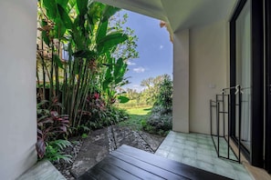 A covered outdoor area with a view of a green landscape, a stone pathway, and a metal railing. - Cozy Room in Mesari Hotel Ubud w Rice Field Views (Gianyar Regency)