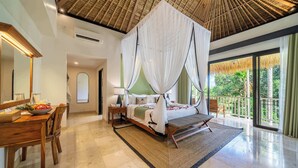 A spacious bedroom with a large bed, a sitting area with a table and chairs, and a balcony with a view of greenery. - Chic Ricefield View Suite in Mesari Hotel - Ubud (Gianyar Regency)
