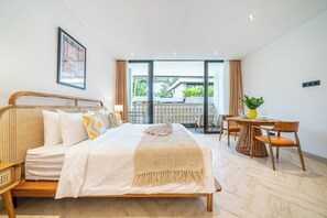 A modern bedroom with a bed, a dining table, and a view of the outdoors. - Stylish Flat with Kitchen in Peaceful Part of Ubud (Gianyar Regency)
