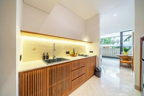 A modern kitchen with a wooden countertop, a sink, and a built-in oven. - Stylish Flat with Kitchen in Peaceful Part of Ubud (Gianyar Regency)